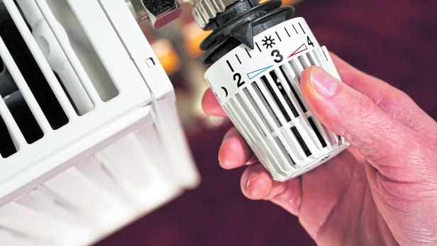 Eine Hand dreht einen Heizkörperthermostat auf Stufe vier.
