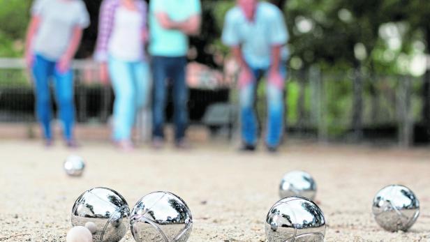 Eine Gruppe von Menschen spielt Boule im Freien.