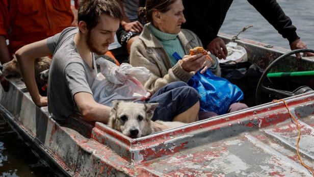 Local residents carry their pets in a boat during evacuation from a flooded area after the Nova Kakhovka dam breached, in Kherson
