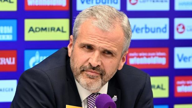 Ein Mann mit einem „Admiral“-Namensschild vor einem violetten Mikrofon und Sponsorenlogos.