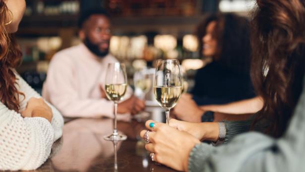 Eine Gruppe von Freunden genießt Weißwein in einem Restaurant.