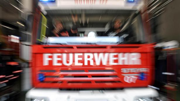 Ein rotes Feuerwehrauto mit Blaulicht fährt schnell.