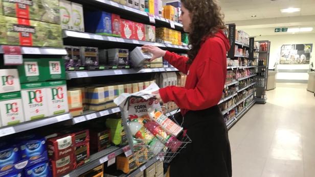 Eine Frau kauft in einem Supermarkt Tee und andere Lebensmittel ein.