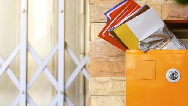 Modern lockable yellow postbox with many mail letter inside. Brick wall and steel doors background.