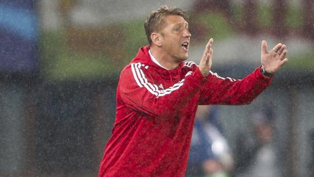 Ein Mann in roter Jacke gestikuliert im Regen.