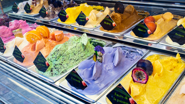 Verschiedene Eissorten, darunter Lavendel, Minze-Schokolade und Passionsfrucht, werden in einem Kühlregal ausgestellt.