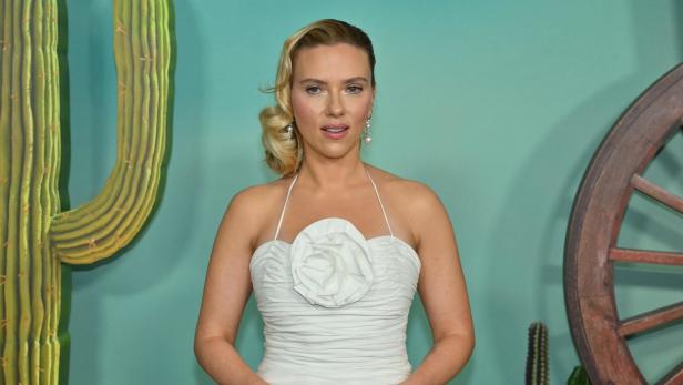Scarlett Johansson in einem weißen Kleid vor einem Wüstenhintergrund.