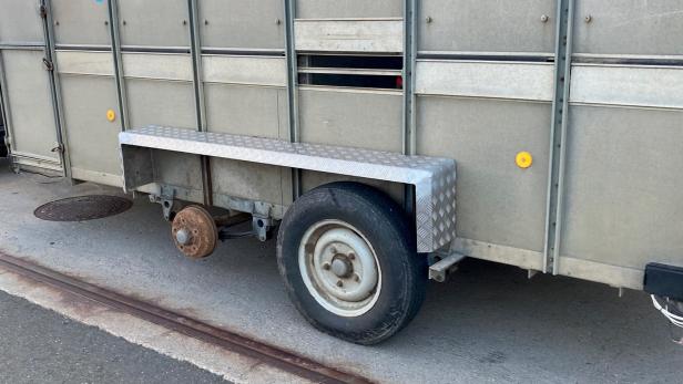 Ein Anhänger mit einem platten Reifen und einer rostigen Radnabe.