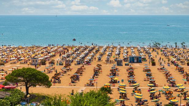 Ein voller Strand mit vielen Sonnenschirmen in Bibione.