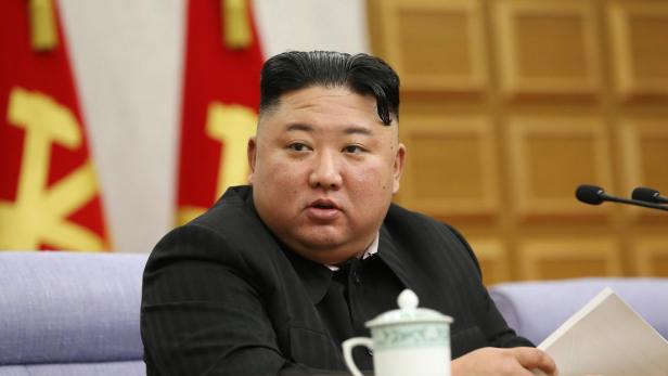 Kim Jong-un sitzt an einem Tisch mit einer Tasse und Dokumenten.