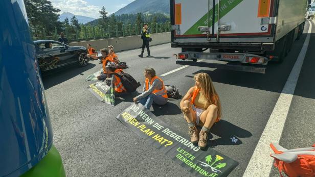 Aktivisten der „Letzten Generation“ blockieren eine Autobahn mit Transparenten.