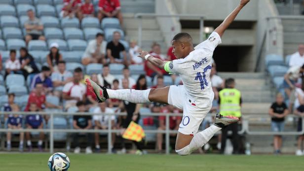 Kylian Mbappé springt, um einen Fußball zu treten.