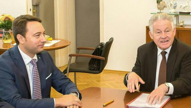 Zwei Männer sitzen an einem Tisch in einem Büro und unterhalten sich.