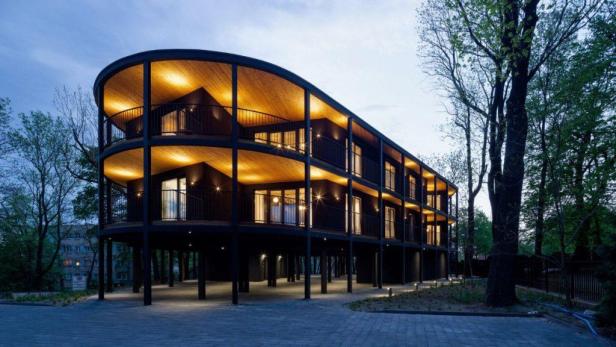 Die moderne Villa Reden mit ihrer markanten Holzverkleidung und den beleuchteten Balkonen.