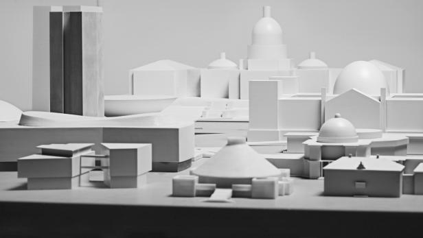 Ein Architekturmodell einer Stadt mit verschiedenen Gebäuden in Graustufen.