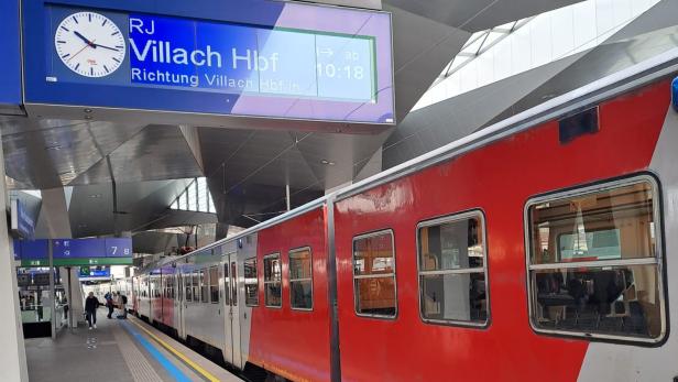 Eine S-Bahn-Garnitur an einem Bahnsteig an dem ein Railjet nach Villach angezeigt wird