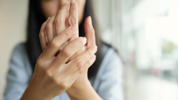 Close-up woman massaging her arthritic hand and wrist, she is suffering from pain and rheumatism.