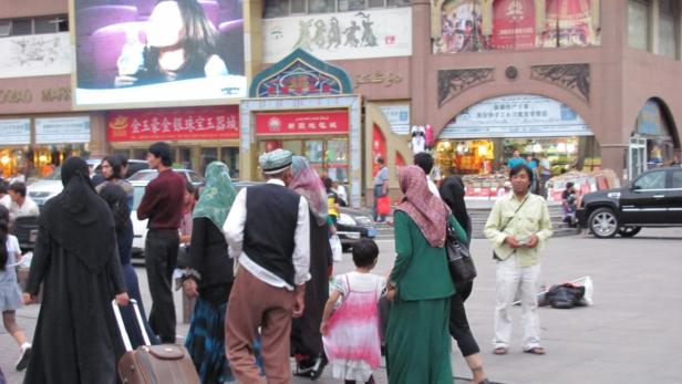 Eine belebte Straße in China mit Menschen und Geschäften im Hintergrund.