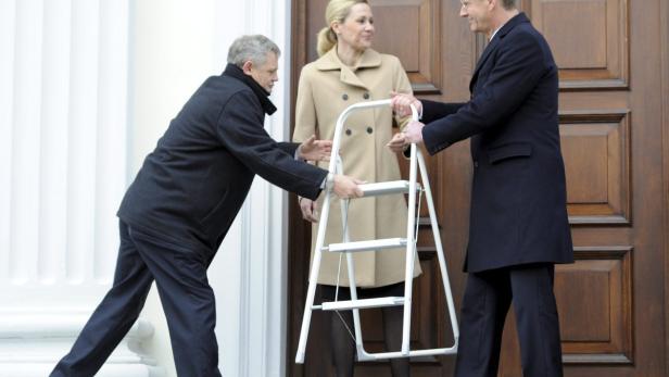 Zwei Männer reichen einer Frau eine weiße Leiter.