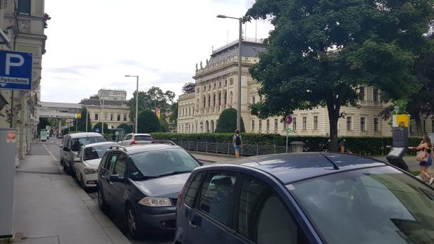 Autos parken am Straßenrand vor einem Gebäude in Wien.