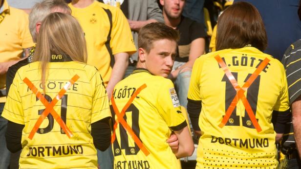 epa03687390 Borussia Dortmund fans wear jerseys with the crossed-out number of Mario Goetze during the German Bundesliga soccer match between Borussia Dortmund and Bayern Munich in Dortmund, Germany, 04 May 2013. Borussia Dortmund forward Mario Goetze will join Bundesliga rivals Bayern Munich at the end of the 2012-13 season. (ATTENTION: EMBARGO CONDITIONS! The DFL permits the further utilisation of up to 15 pictures only (no sequential pictures or video-similar series of pictures allowed) via the internet and online media during the match (including halftime), taken from inside the stadium and/or prior to the start of the match. The DFL permits the unrestricted transmission of digitised recordings during the match exclusively for internal editorial processing only (e.g. via picture databases) EPA/BERND THISSEN