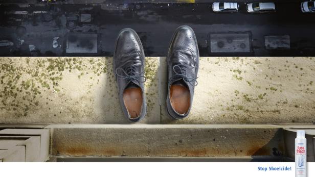 Ein Paar abgenutzte Lederschuhe stehen auf einem Dachvorsprung.