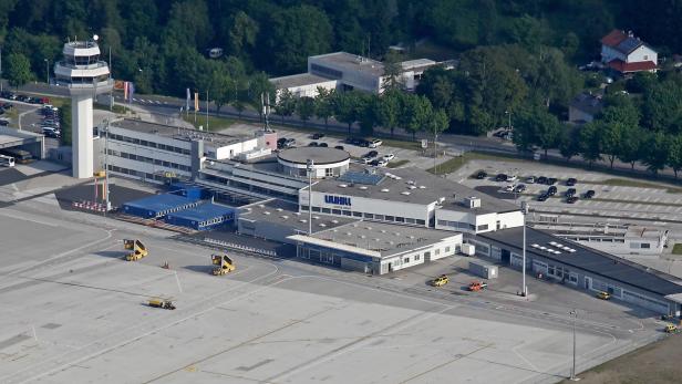Luftaufnahme des Flughafens Klagenfurt mit Kontrollturm und Parkplätzen.