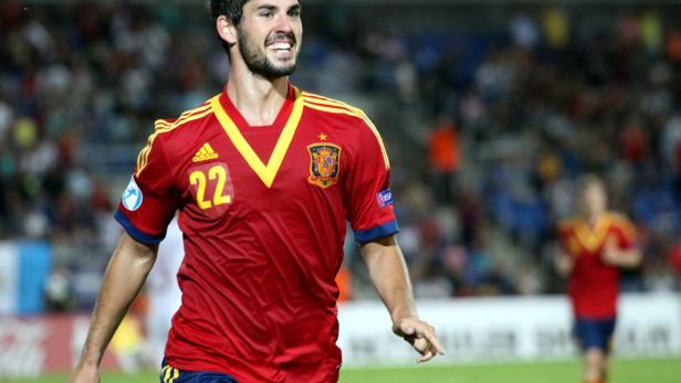 Ein spanischer Fußballspieler im rot-gelben Trikot mit der Nummer 22 lächelt.