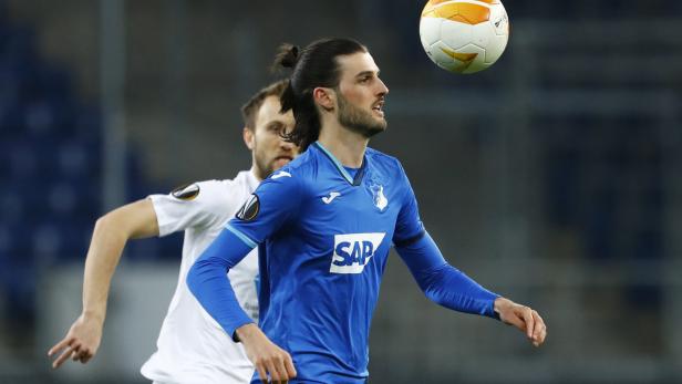 Ein Fußballspieler in blauem Trikot köpft einen Ball.