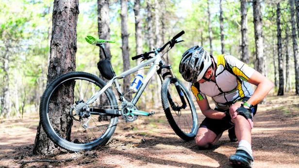 Ein Mountainbike-Fahrer reibt sich sein schmerzendes Knie.