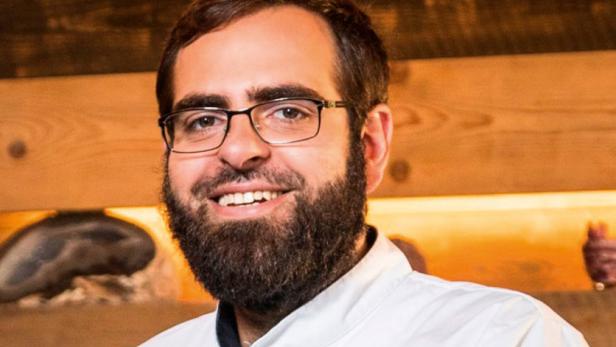 Alexander Posch lächelt in seiner Kochuniform.