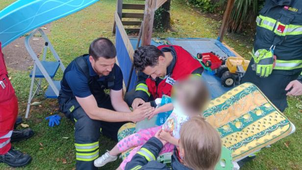 Sanitäter versorgen ein verletztes Kind auf einem Spielplatz.