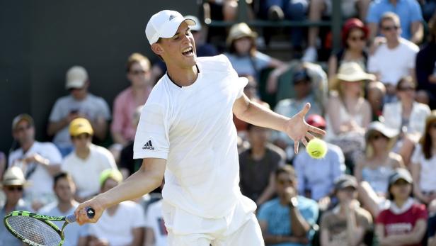 Ein Tennisspieler schlägt einen Ball vor einer Zuschauermenge.