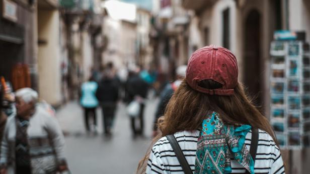 Eine Touristin geht eine belebte Straße entlang.
