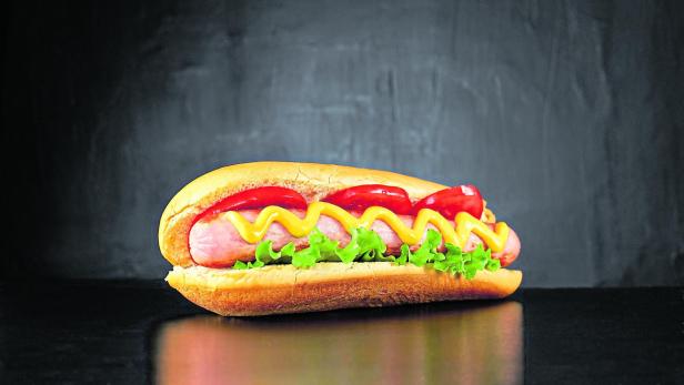 Big hotdog with sausage tomatoes, mustard and salad isolated