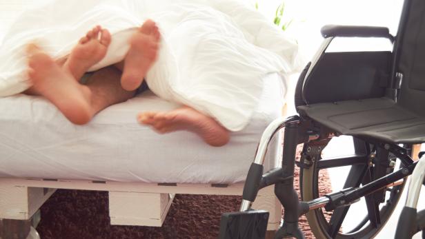 Disabled man having sex in bed with his partner.