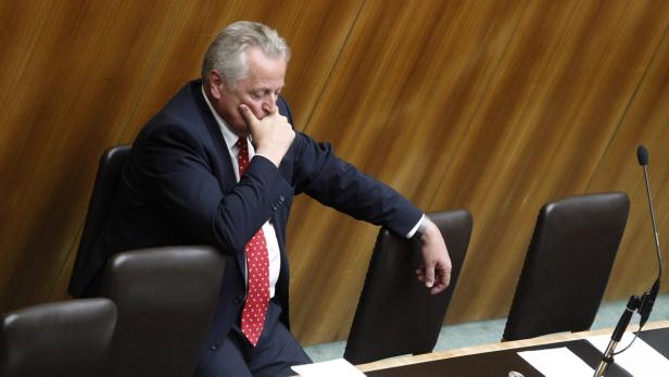 Ein Mann im Anzug sitzt nachdenklich in einem Konferenzraum.