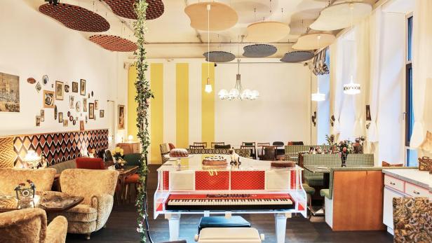 Ein Innenraum mit einem Klavier, Sesseln und dekorativen Elementen an der Decke.