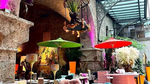 Ein Innenhof mit Tischen, Stühlen und farbenfrohen Dekorationen für ein besonderes Ambiente.