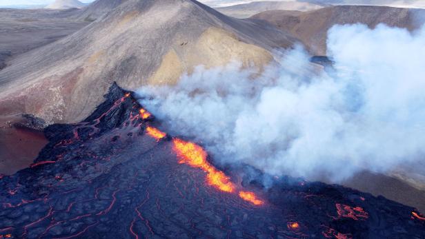 Ein Vulkan spuckt Lava und Rauch in einer bergigen Landschaft.