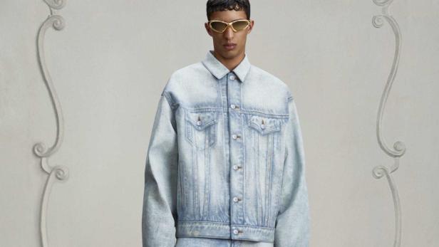 Ein Mann mit Sonnenbrille trägt ein Jeansjacke und Jeanshose.