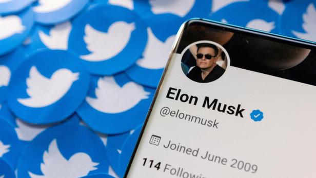 Illustration von Elon Musks Twitter-Profil auf einem Smartphone und gedruckten Twitter-Logos.