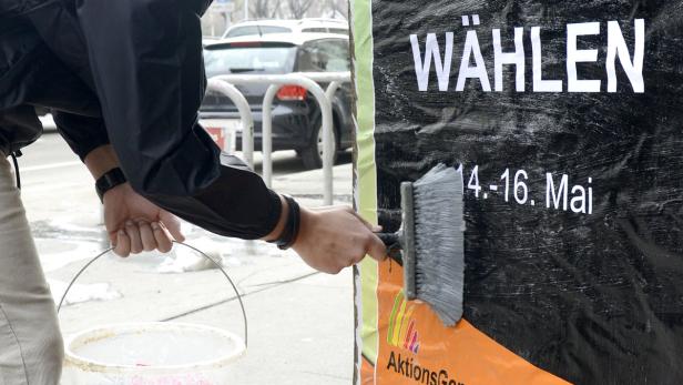 Eine Person beklebt eine Wahlplakatwand mit dem Hinweis „Wählen“.