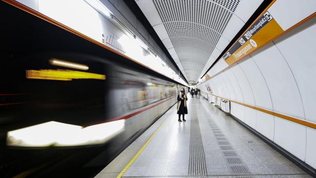 U-Bahn-Station mit einfahrendem Zug und wartenden Fahrgästen auf dem Bahnsteig.