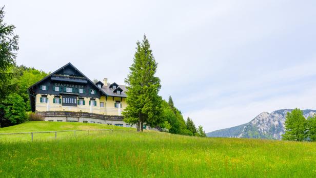 Der KnappenHof liegt auf einer grünen Wiese mit Blick auf die Berge.