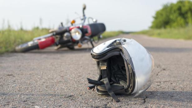 Photo of helmet and motorcycle on the road, the concept of road accidents
