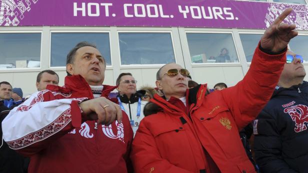 Wladimir Putin und ein weiterer Mann beobachten ein Sportereignis.