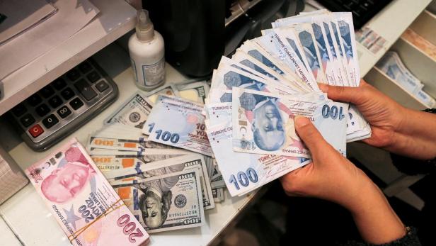 FILE PHOTO: A money changer holds Turkish lira banknotes at a currency exchange office in Ankara
