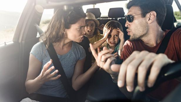 Eltern streiten im Auto, Kinder sitzen auf der Rückbank und halten sich die Ohren zu, Krise im Urlaub