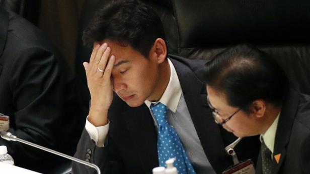 Ein Mann mit Anzug und Krawatte stützt seinen Kopf mit der Hand.